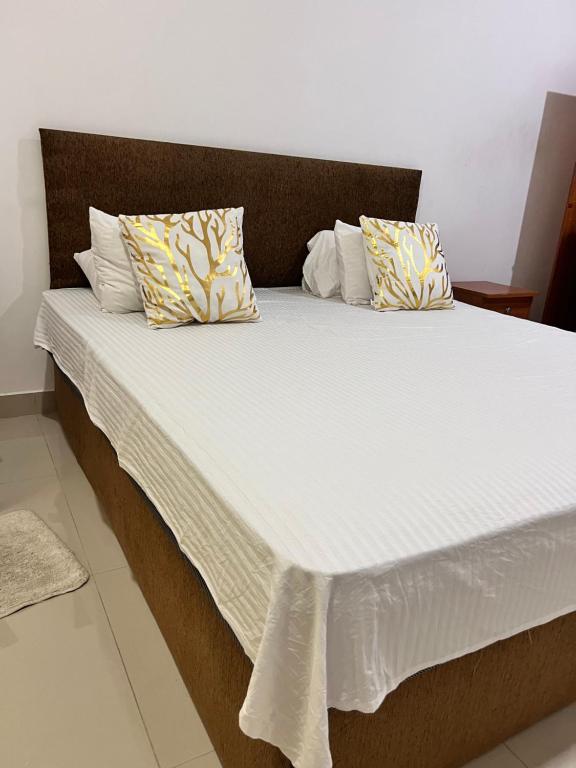 1 cama grande con sábanas blancas y almohadas. en R&R residencies en Mount Lavinia