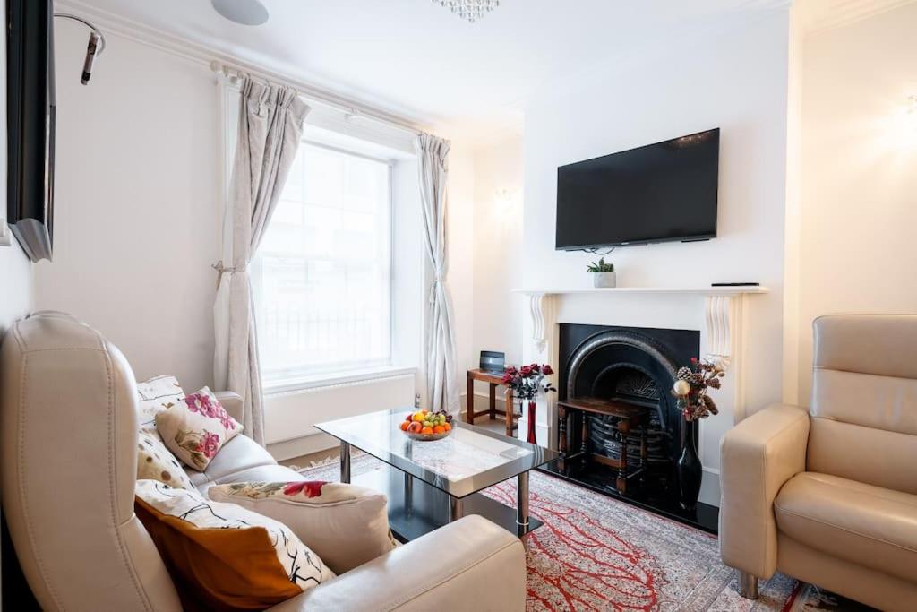 ein Wohnzimmer mit einem Sofa und einem Kamin in der Unterkunft Spacious, Bright & Cosy ~ Ideal Victoria Location! in London