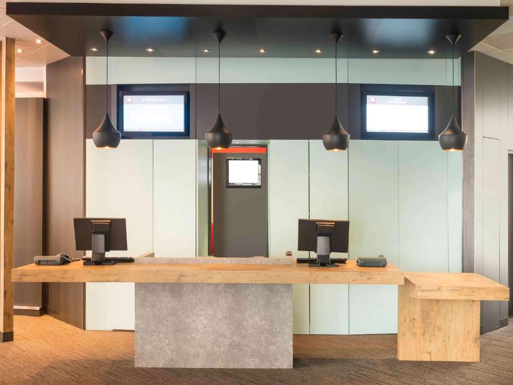 a conference room with a wooden table with two monitors at ibis Nantes Centre Tour Bretagne in Nantes