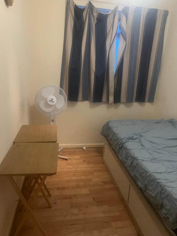 Schlafzimmer mit einem Bett, einem Schreibtisch und einem Fenster in der Unterkunft Affordable Room to Rent for Short Stay in Abbey Wood