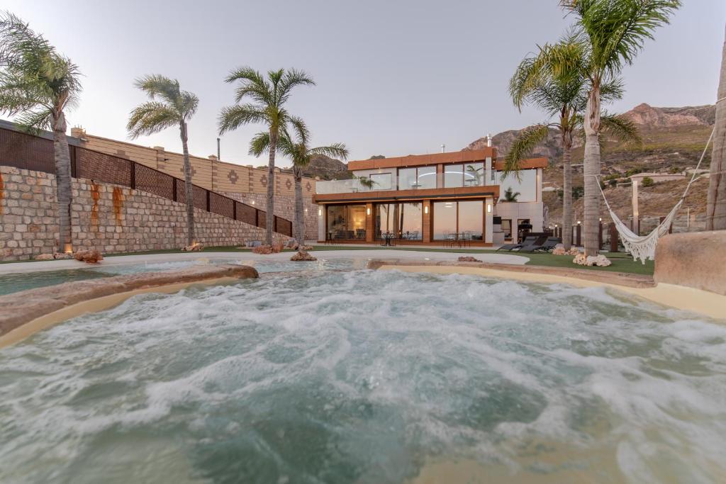 une maison avec une piscine bordée de palmiers dans l'établissement Casa Playa Cristal Piscina Infinita con Arena, à Molvízar