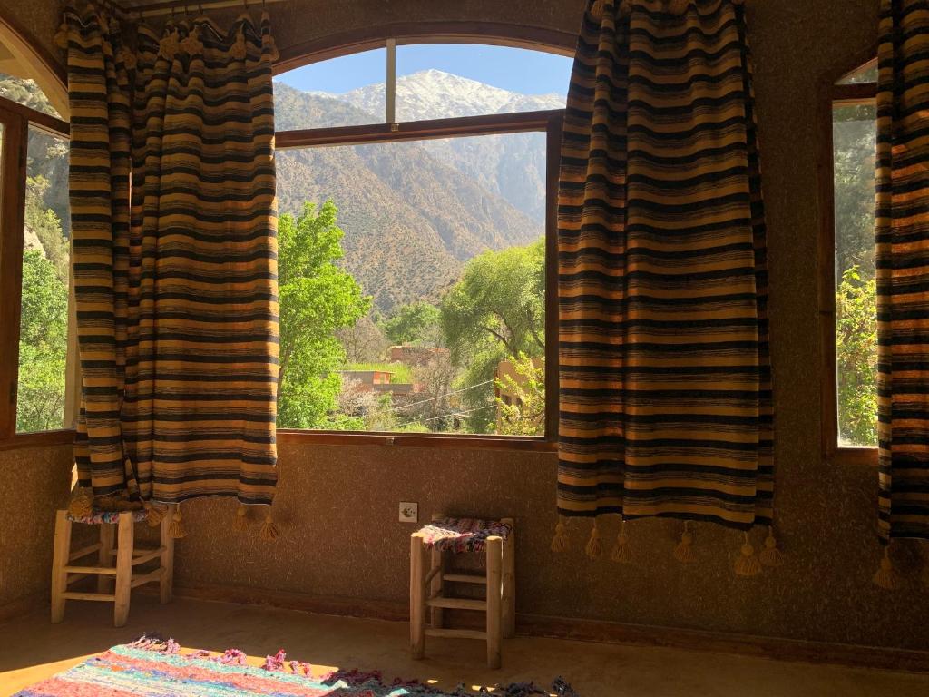 een kamer met een groot raam met uitzicht op de bergen bij Guest House Tigminou in Setti Fatma