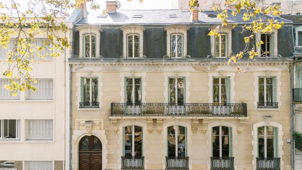 a large building with a balcony on the side of it at Les Suites de L’Opéra in Vichy