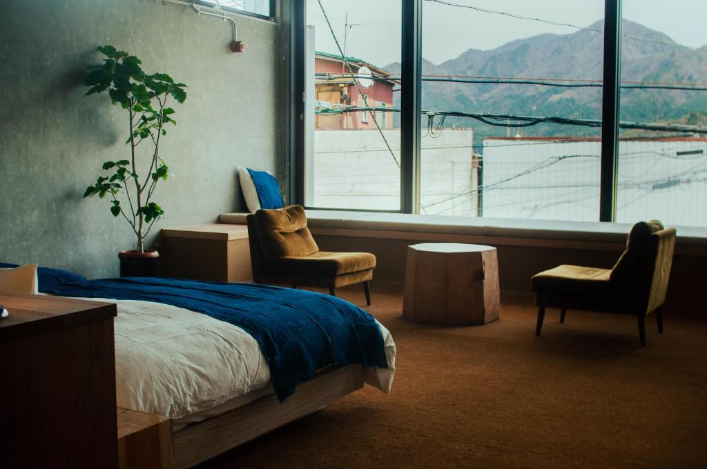 a bedroom with a bed and two chairs and a large window at Hostel Saruya in Fujiyoshida