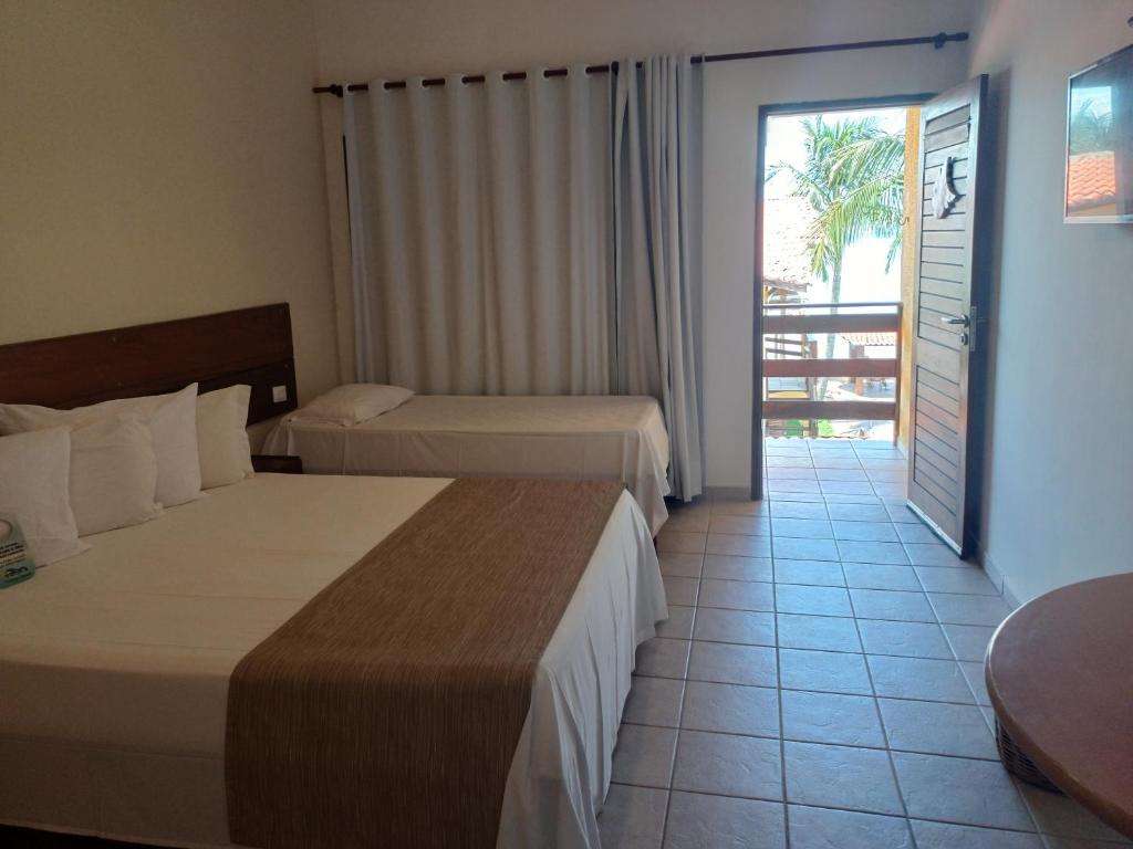 a hotel room with two beds and a balcony at Pousada Vivenda Oriente in São José da Coroa Grande
