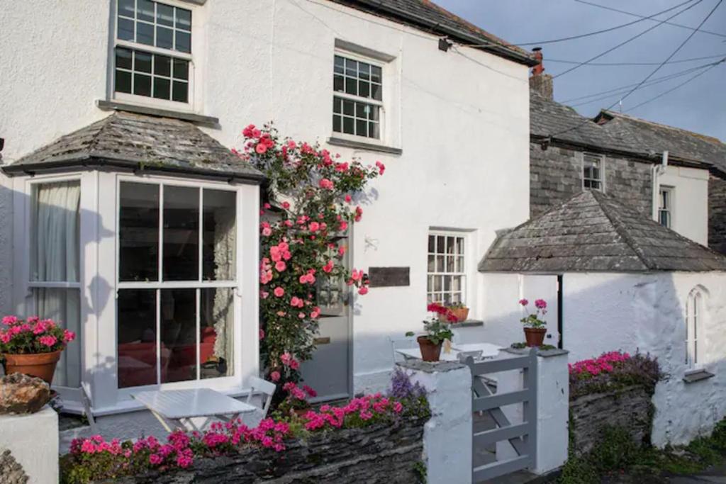 a white house with flowers in front of it at Geranium Cottage in Port Isaac