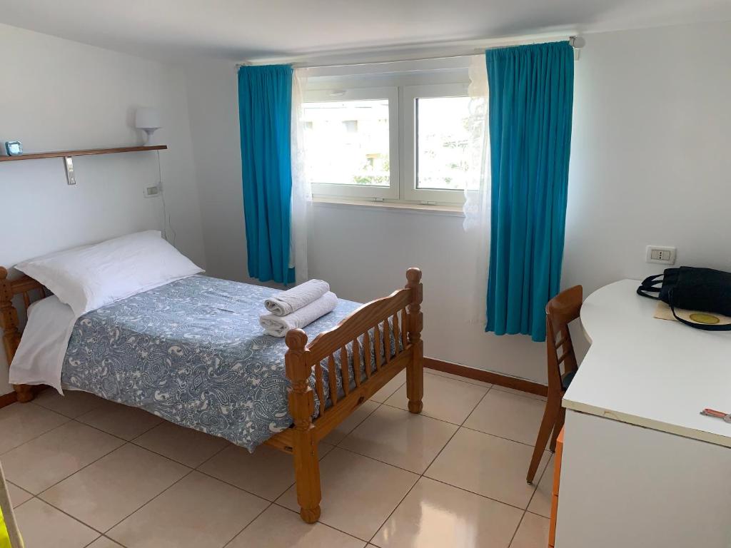 1 dormitorio con 1 cama y una ventana con cortinas azules en B&B74, en Pescara