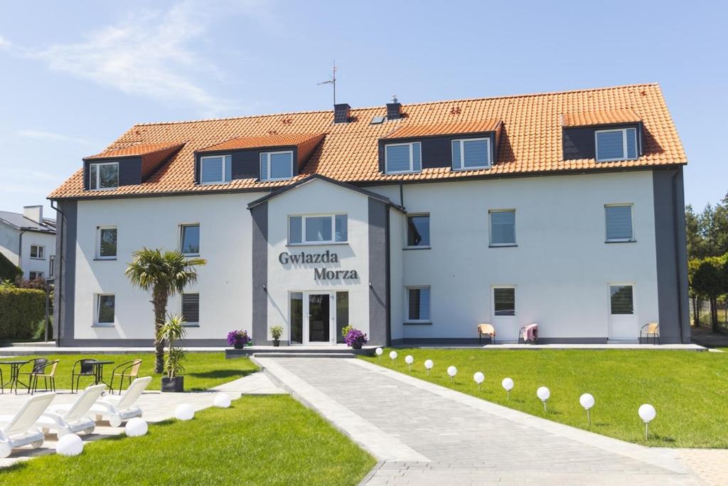 a large white building with chairs in front of it at Gwiazda Morza in Sianozety