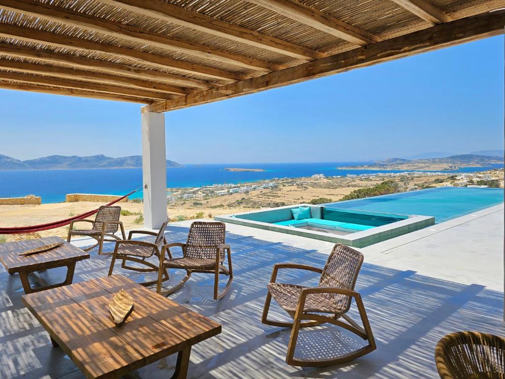 un patio con sillas y mesas y vistas al océano en Lefki Sokolata, en Koufonisia