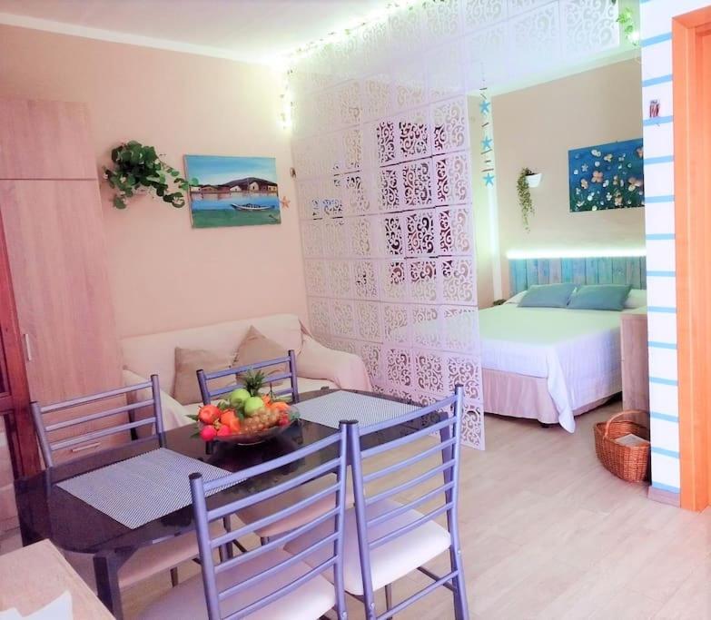Zimmer mit einem Tisch und Stühlen sowie einem Schlafzimmer in der Unterkunft Grazioso monolocale in Sardegna in Marina di Sorso