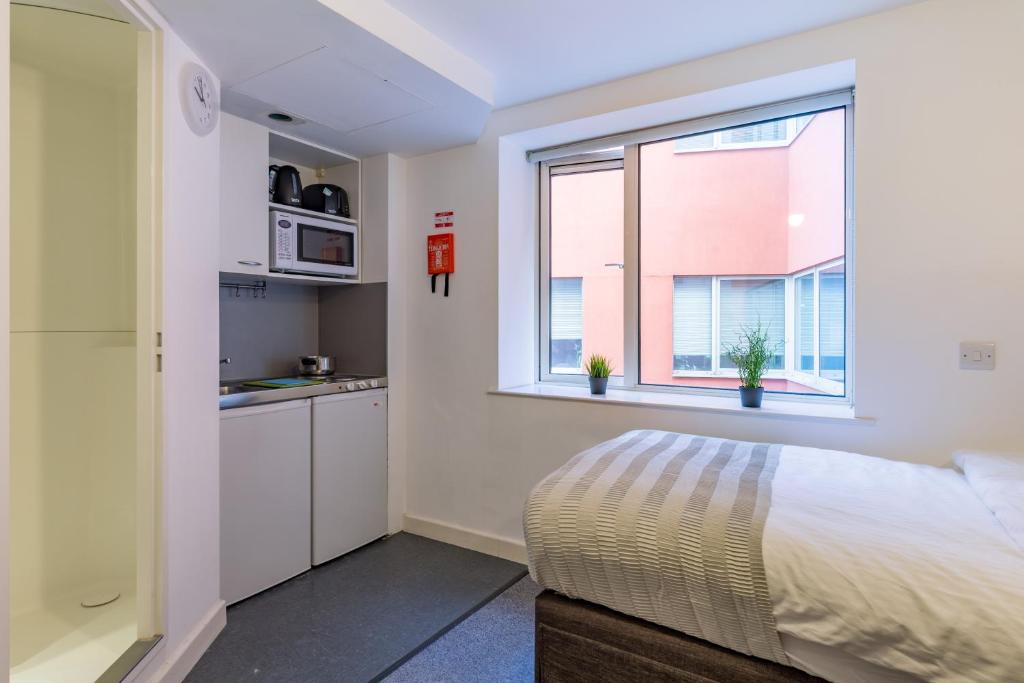 1 dormitorio con 1 cama y cocina con ventana en Studio Flat Farringdon, en Londres