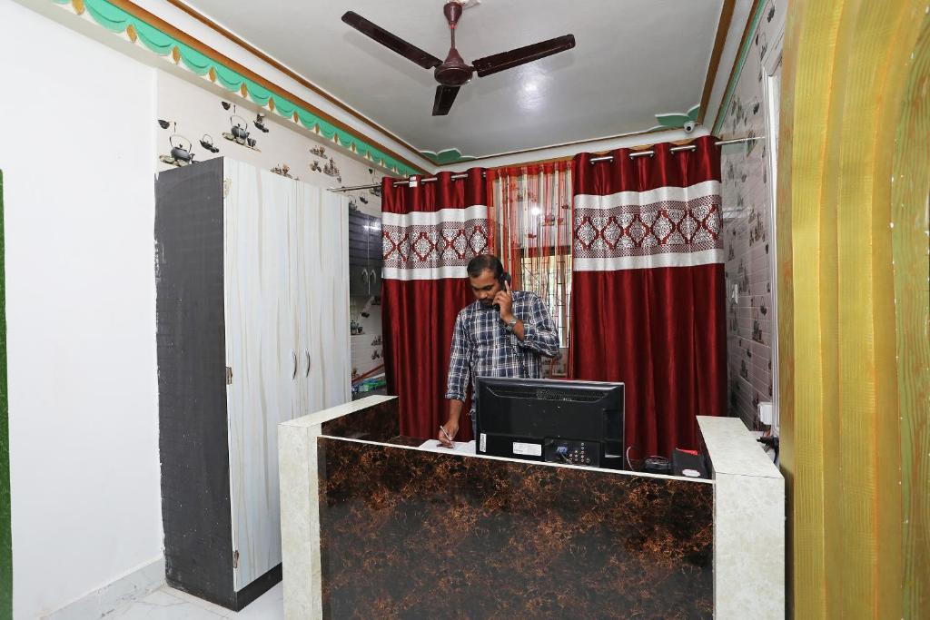 a man talking on a cell phone in a room with red curtains at OYO Aradhya Residency in Bhubaneshwar