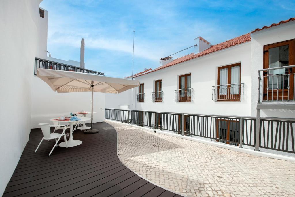 a balcony with a table and an umbrella at Porta da Arrábida Suites in Palmela