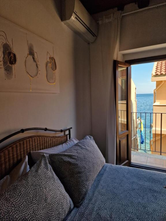um quarto com uma cama e vista para o oceano em LA CASETTA AZZURRA CHIANALEA - locazione turistica em Scilla
