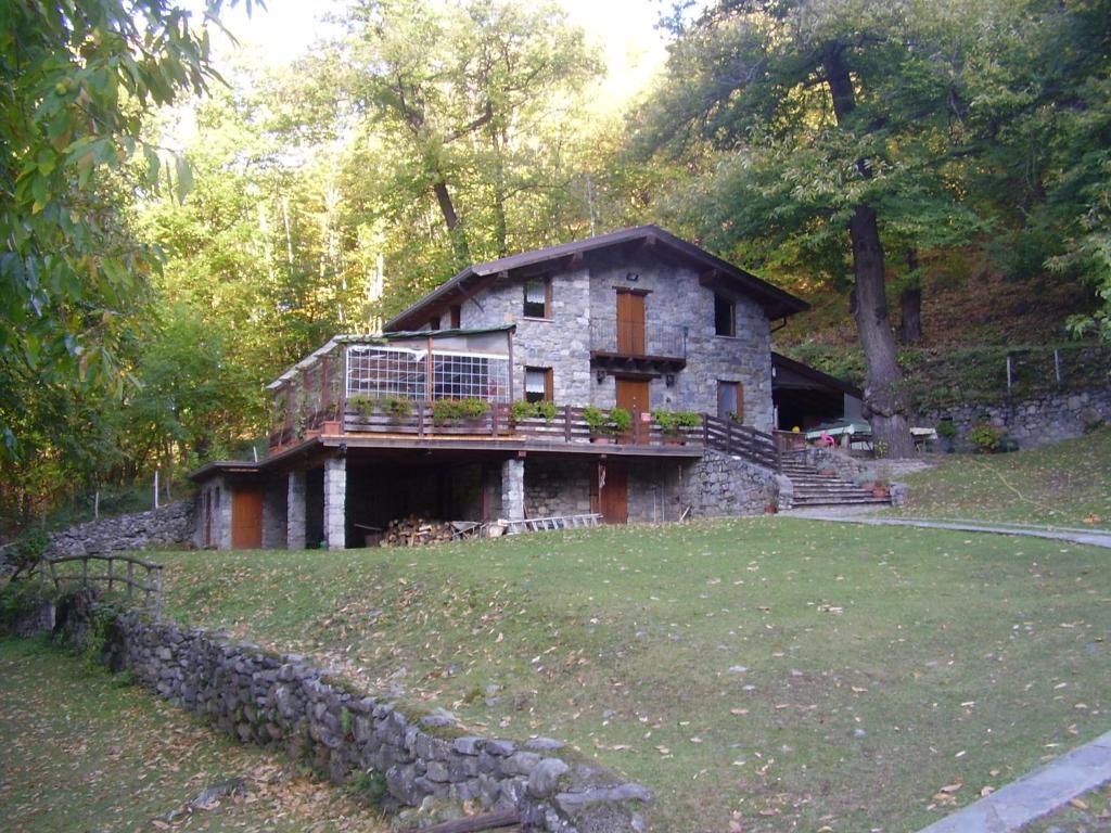 a stone house with a balcony on top of a yard at agriturismo il riccio in Cedegolo
