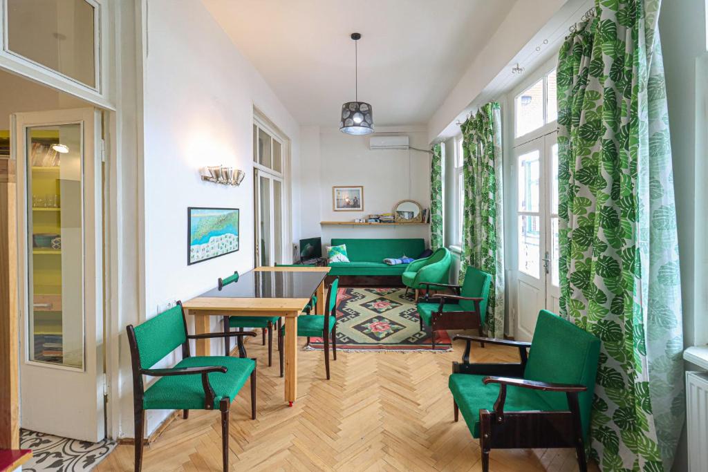 uma sala de estar com cadeiras verdes e uma mesa em INOLA Sunny flat with balcony in central Tbilisi em Tbilisi