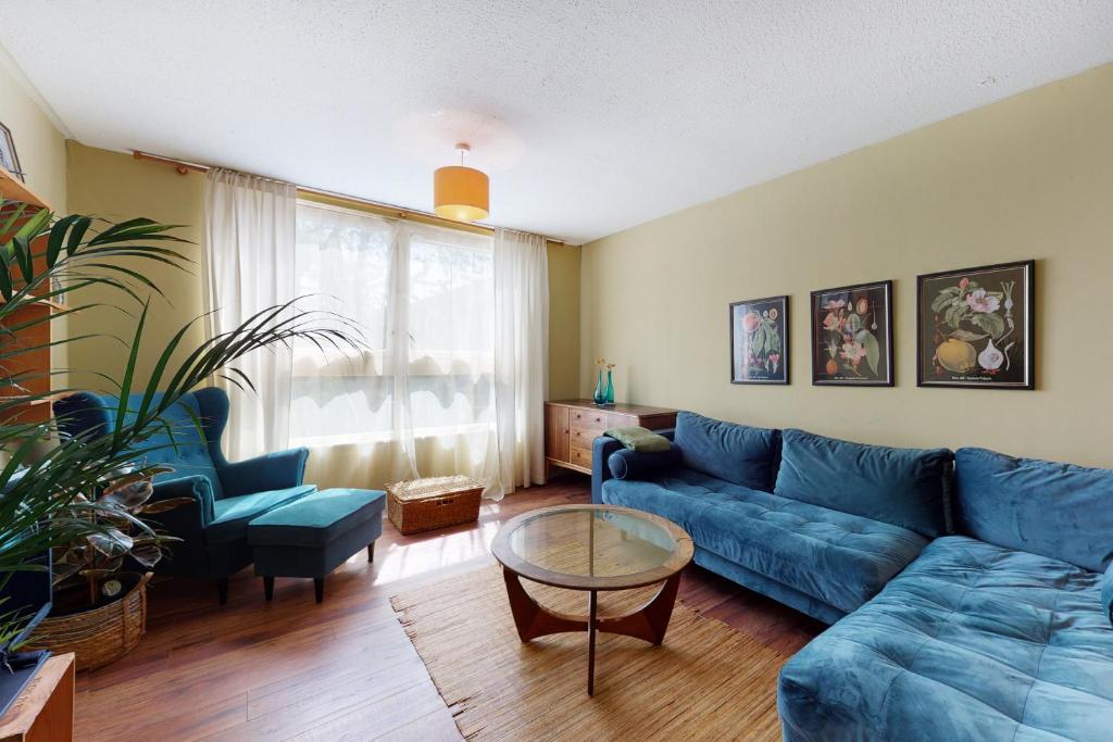uma sala de estar com um sofá azul e uma mesa em 3bed house with patio & parking - 9 min to Station em Londres