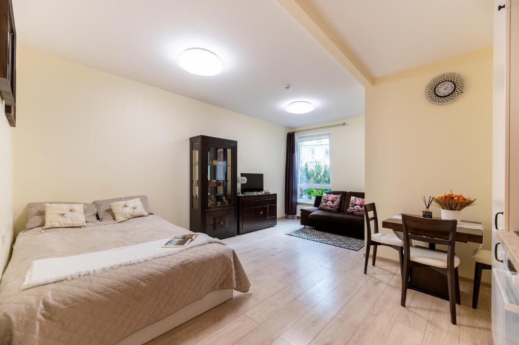 a bedroom with a bed and a table and a desk at Ozo park apartments in Vilnius