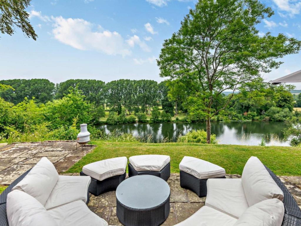 un patio con mesa, sillas y un lago en Riverside House en Cookham