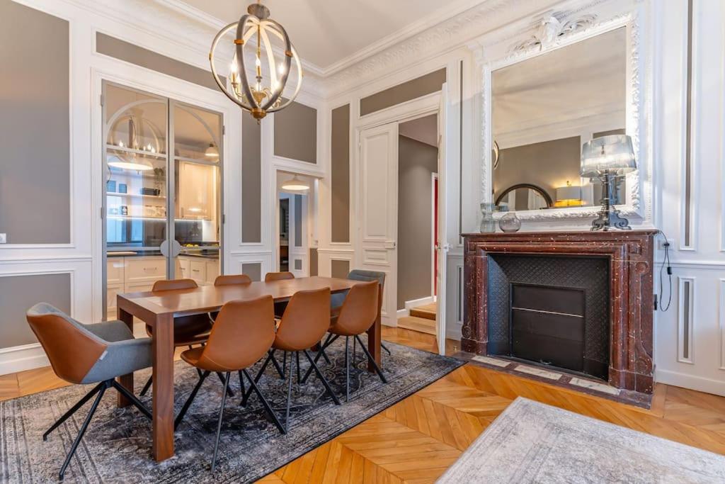 een eetkamer met een tafel en een open haard bij Appartement de luxe in Parijs
