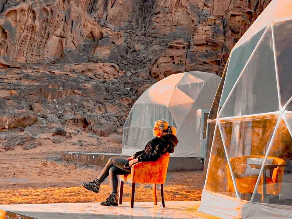 a person sitting in a chair in front of a tent at Traditions of Wadi Rum camp & jeep tour in Wadi Rum