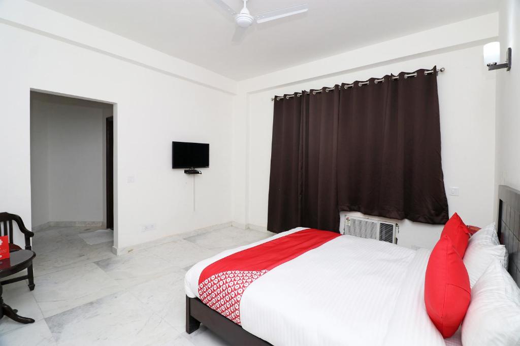 una camera da letto con un letto con cuscini rossi e una TV di Super OYO The Primero Near Leisure Valley Park a Gurgaon