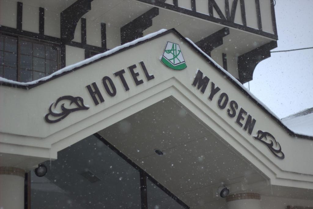 a sign for a hotel in the snow at Hotel Myosen in Myoko