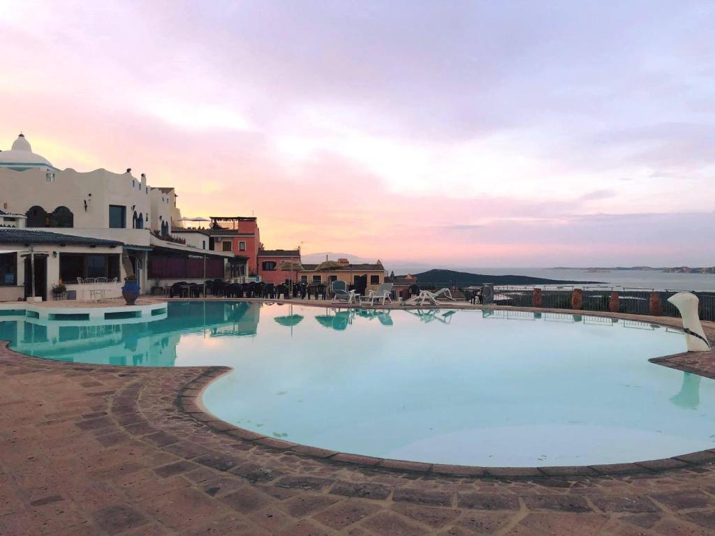 a large swimming pool with a sunset in the background at Anima Rooms & Pool in San Pasquale
