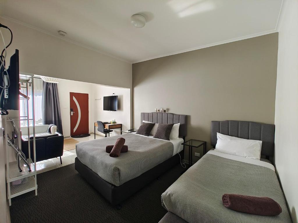 a hotel room with two beds and a chair at Altair Motel in Cooma