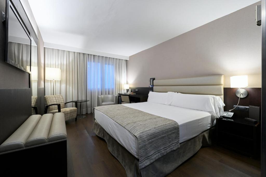 a hotel room with a large bed and a chair at Catalonia Rigoletto in Barcelona