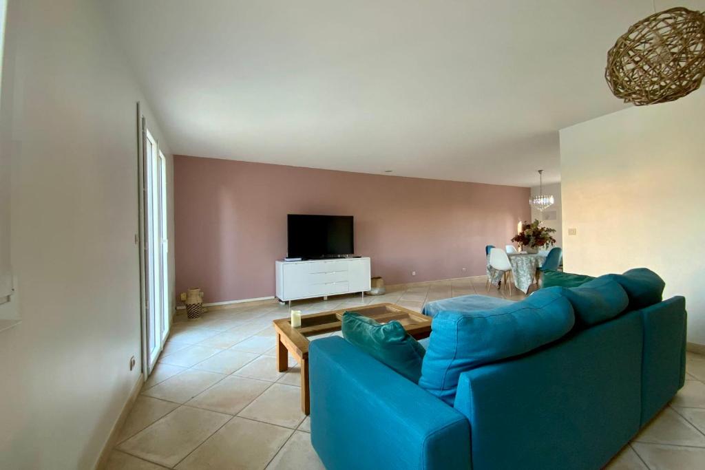 ein Wohnzimmer mit einem blauen Sofa und einem TV in der Unterkunft La Castelnauvienne- 3 bedroom villa with swimming pool! in Castelnau-le-Lez