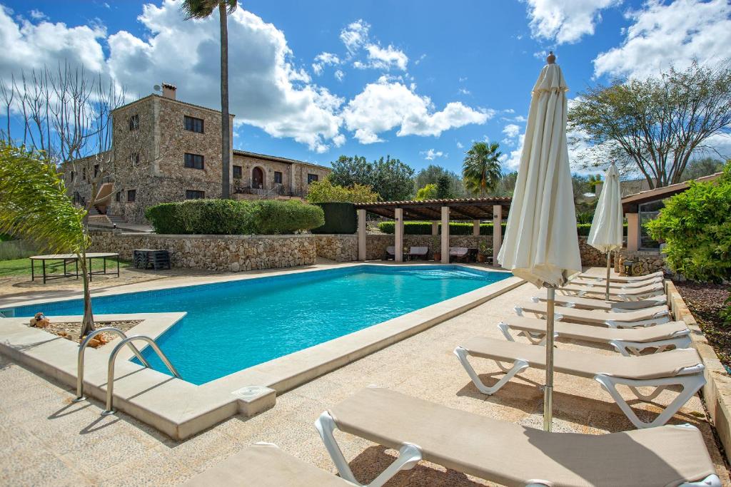 a swimming pool with lounge chairs and an umbrella at Agroturismo Ses Illes in Costitx