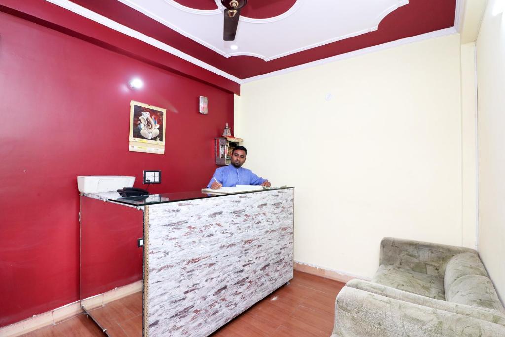 a man sitting at a counter in a red room at Flagship Hotel Sweet Night in Ghaziabad