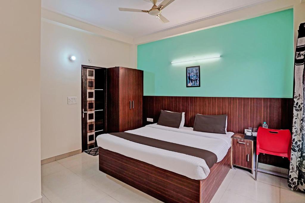 a bedroom with a large bed and a red chair at OYO Golden Imperial Near PVR Ansal Plaza Greater Noida in Greater Noida