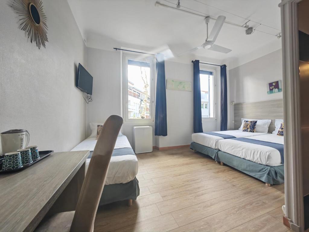 Zimmer mit 2 Betten, einem Schreibtisch und 2 Fenstern in der Unterkunft Les Lavandes in La Ciotat