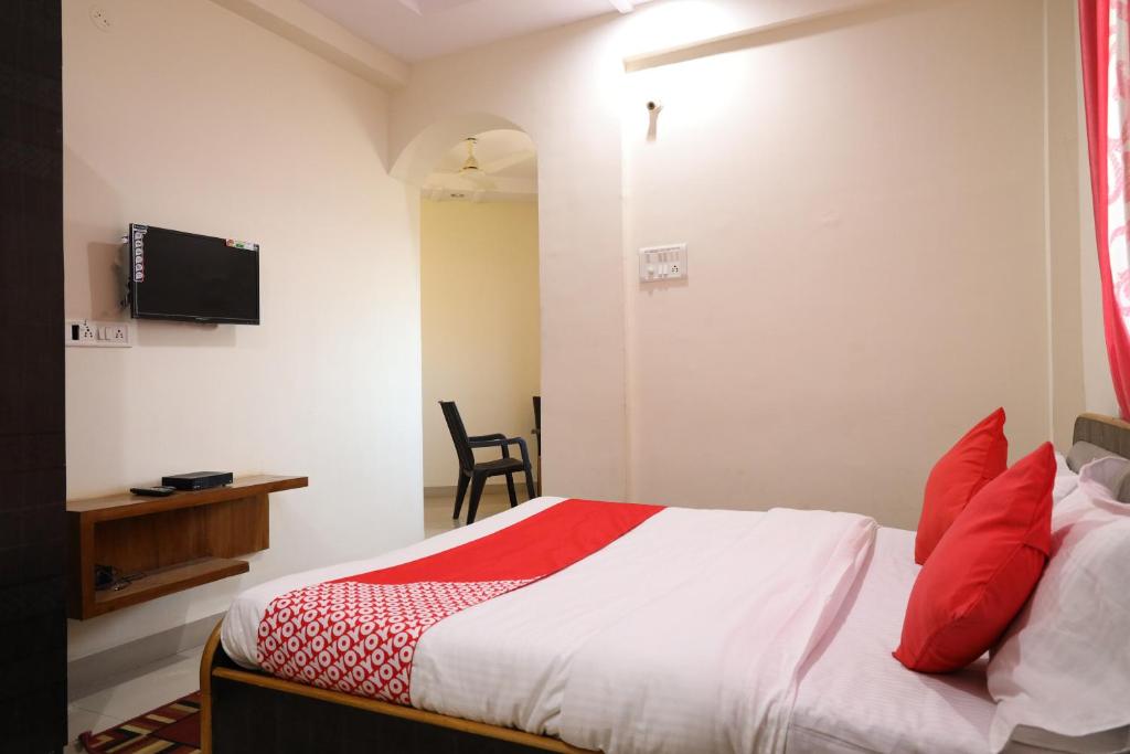 a bedroom with a bed with red pillows and a television at OYO Prithvi Inn in Dhantoli