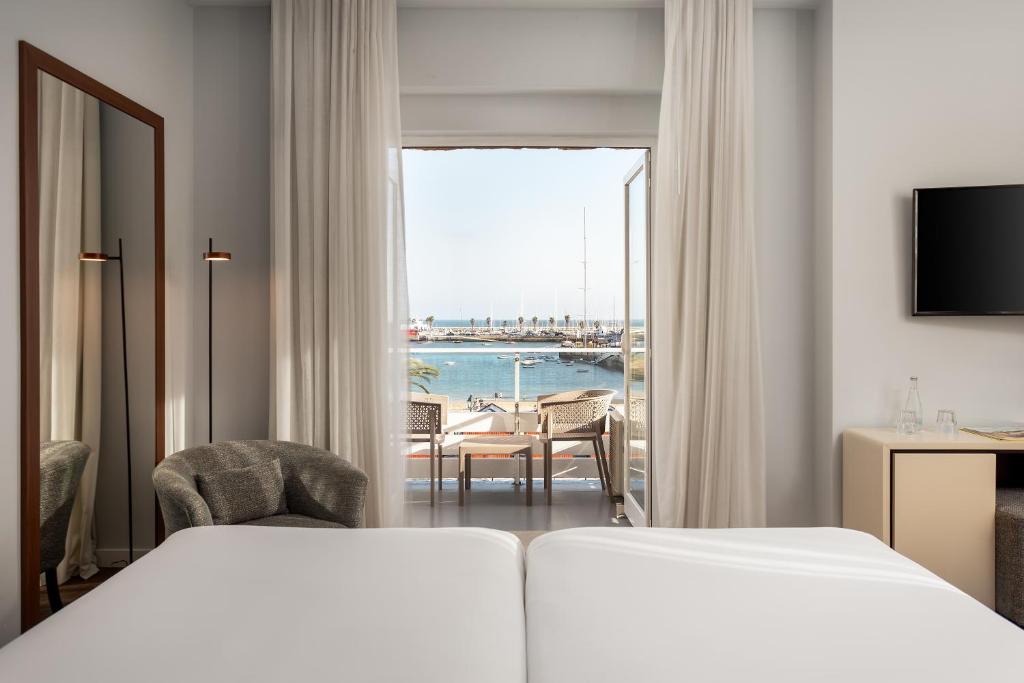 a hotel room with a bed and a view of the ocean at Hotel Baia in Cascais