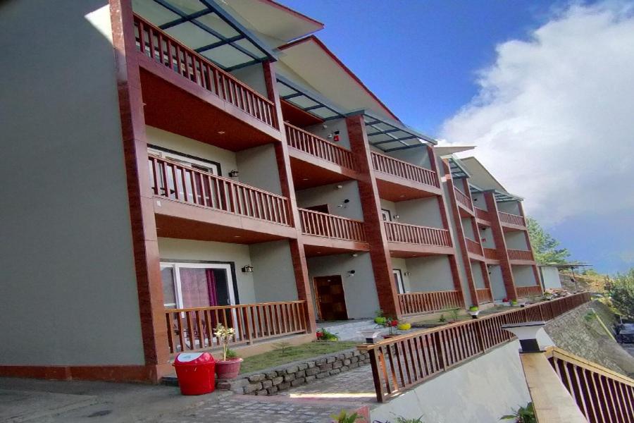 a large building with balconies on the side of it at Satine Resort Auli in Joshīmath