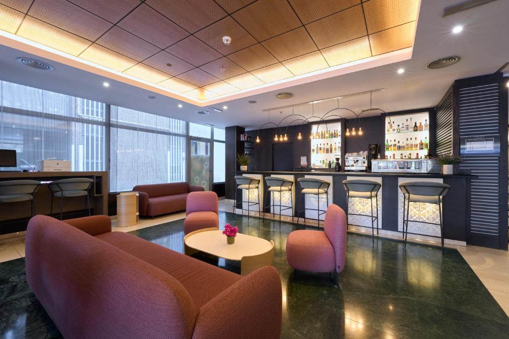 a hotel lobby with a bar with pink chairs at Catalonia Rigoletto in Barcelona