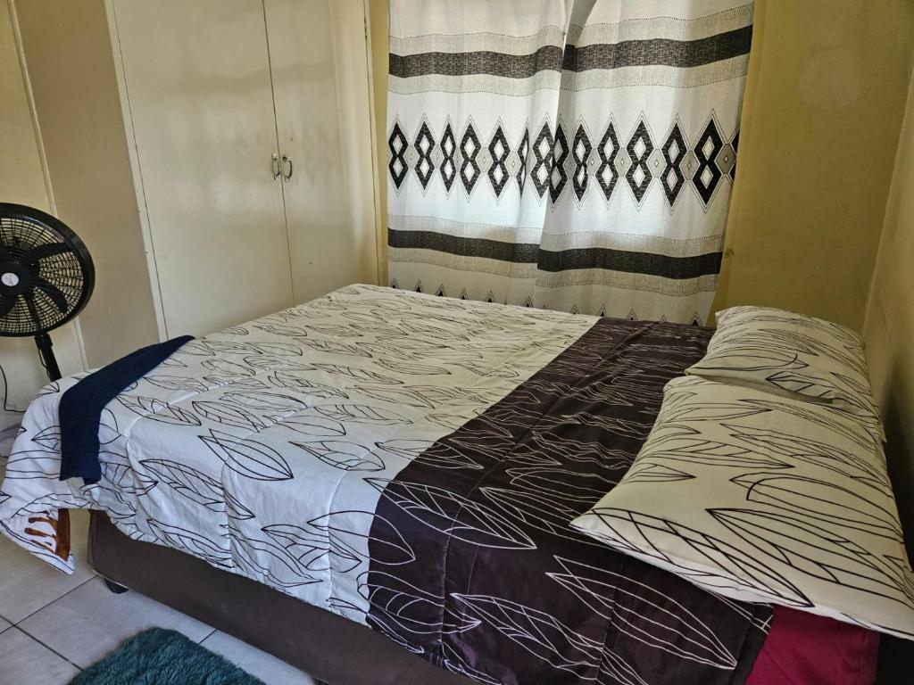 een bed in een kamer met een gordijn bij Stay Sunrise in Nelspruit