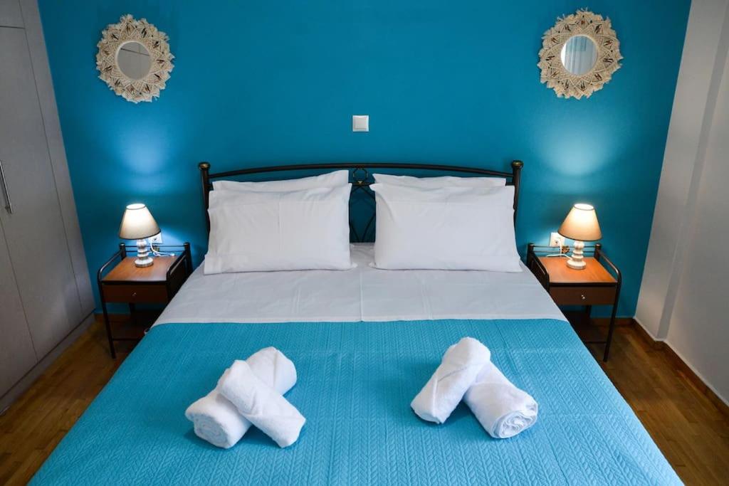een blauwe slaapkamer met een bed met twee witte handdoeken erop bij Dream apartment in Kallithea in Athene