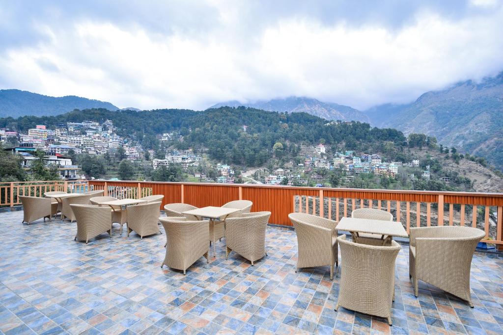 um grupo de mesas e cadeiras numa varanda com montanhas em Hotel Pawan Regency Mcleodganj em McLeod Ganj