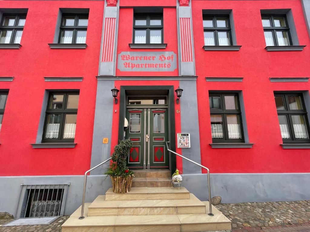 un edificio rojo con una puerta delantera roja y escaleras en Warener Hof Apartments, en Waren