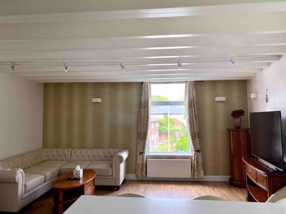 een woonkamer met een bank en een raam bij Contemporary Duplex: Private Patio, Secure Parking in Stockport