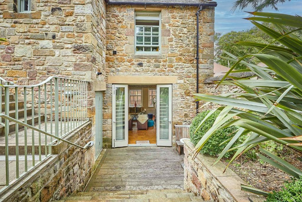 a stone house with a staircase leading to the front door at Spence Lodge: Beautiful 2-Bedroom Stone Cottage in Alnmouth