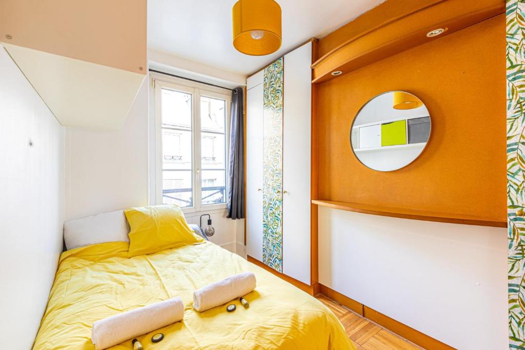 - une chambre avec un lit jaune et un miroir dans l'établissement GuestReady - Apt clair et spacieux à Paris !, à Paris