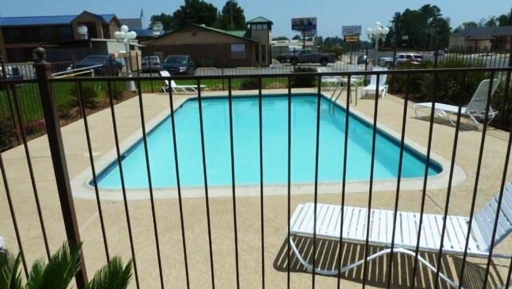 een zwembad achter een hek met een bankje ernaast bij Xecutive Inn and Suites in Center
