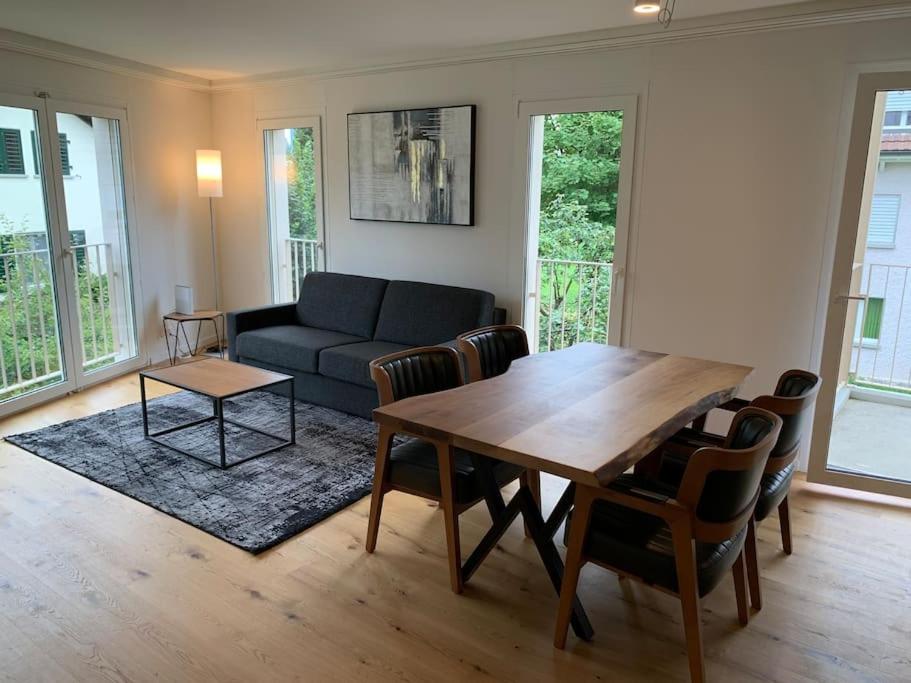 uma sala de estar com uma mesa de madeira e um sofá em Modern one bedroom flat close to the city - Bass1 em Bassersdorf