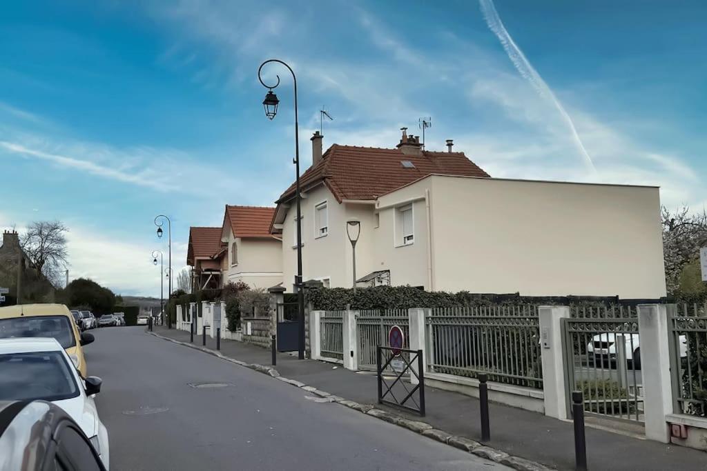 a white house on a street with a fence at Chaleureux et Cosy proche Gare in Massy