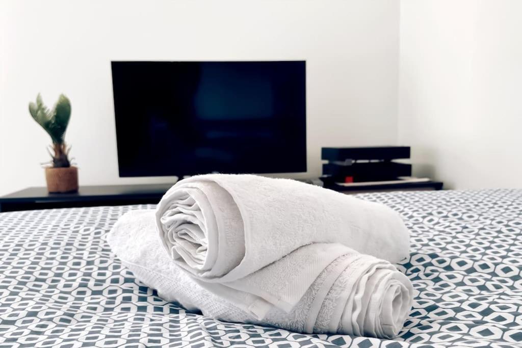 a white towel laying on a bed with a flat screen tv at Chaleureux et Cosy proche Gare in Massy